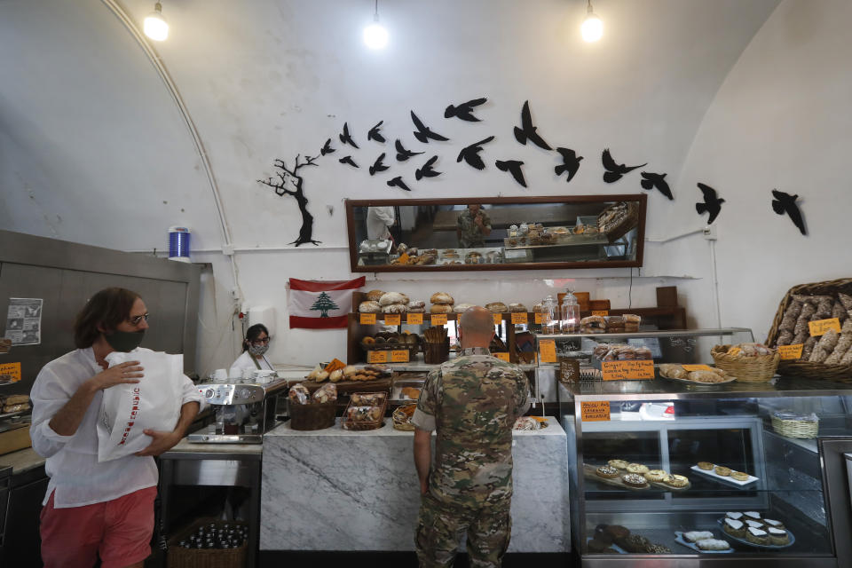 Customers buy bread on June 18, 2020, at the Bread Republic bakery owned by Walid Ataya, who also has a restaurant, pizzeria, wine room and flower shop on a strategic intersection leading into an upscale neighborhood in Beirut, Lebanon. Ataya had to close all but the bakery and flower shop for nearly three months during Lebanon's strict and early lockdown imposed in March. (AP Photo/Hussein Malla)