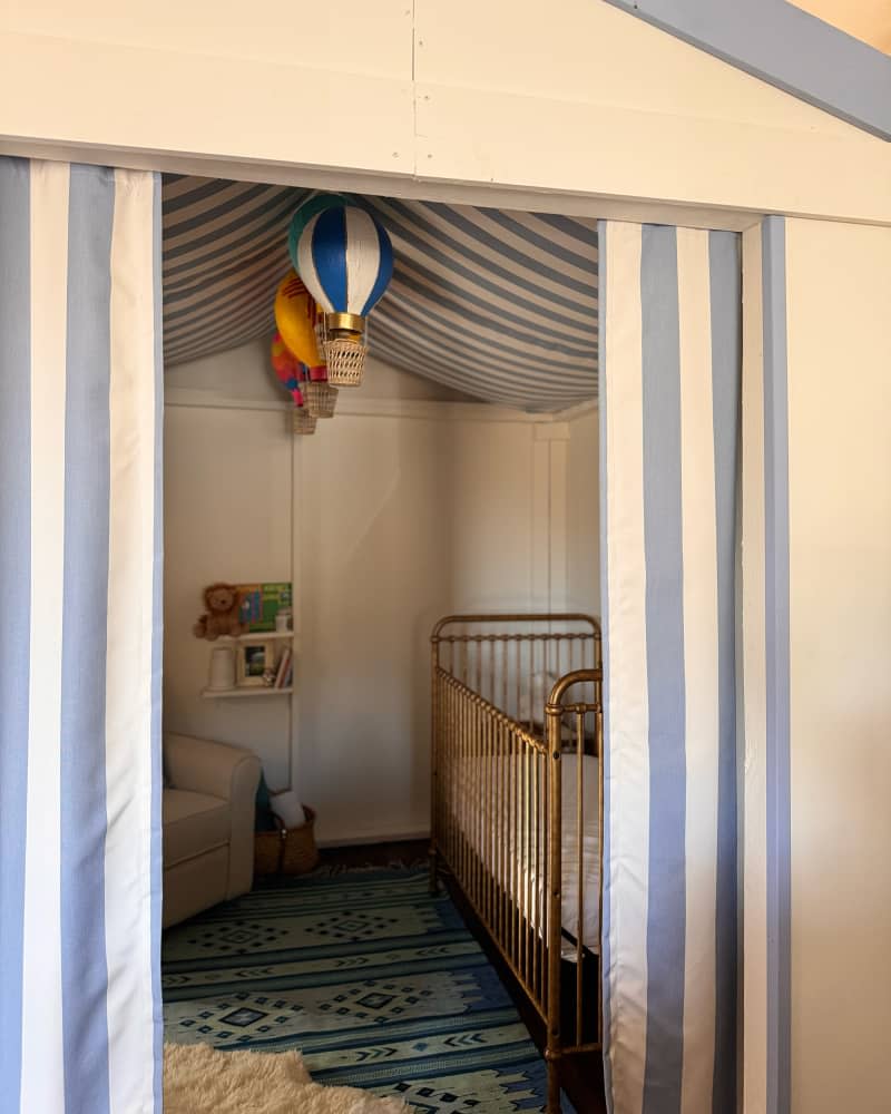 Blue and white striped fabric in DIY built circus themed tent in nursery.