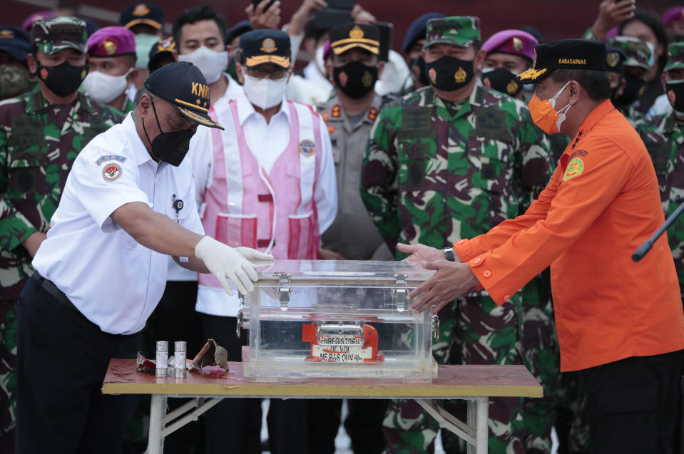 Chief of National Transportation Safety Committee Soerjanto Tjahjono, left, and Chief of National Search and Rescue Agency, Bagus Puruhito, right, hold the box containing the flight data recorder of Sriwijaya Air flight SJ-182 retrieved from the Java Sea where the passenger jet crashed as, rear from left, Armed Forces Chief Mair Marshall Hadi Tjahjanto, Transportation Minister Budi Karya Sumadi, and Navy Chief of Staff Admiral Yudho Margono look on, during a press conference at Tanjung Priok Port, Tuesday, Jan. 12, 2021. Indonesian navy divers searching the ocean floor on Tuesday recovered the flight data recorder from a Sriwijaya Air jet that crashed into the Java Sea with 62 people on board. (AP Photo/Dita Alangkara)