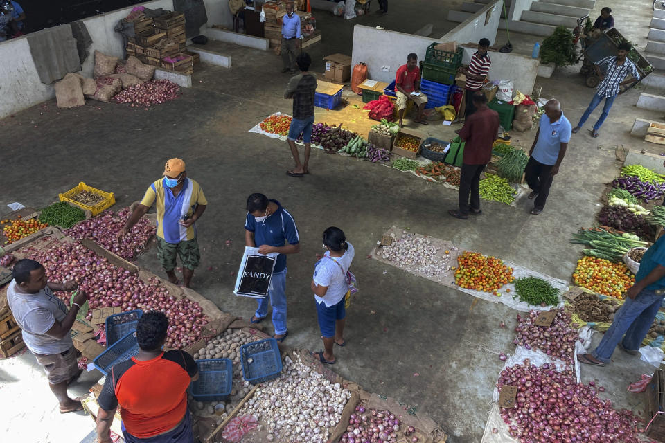 People purchase imported onions and garlic at a market in Colombo, Sri Lanka, Sunday, June 26, 2022. Sri Lankans have endured months of shortages of food, fuel and other necessities due to the country's dwindling foreign exchange reserves and mounting debt, worsened by the pandemic and other longer term troubles. (AP Photo/Eranga Jayawardena)