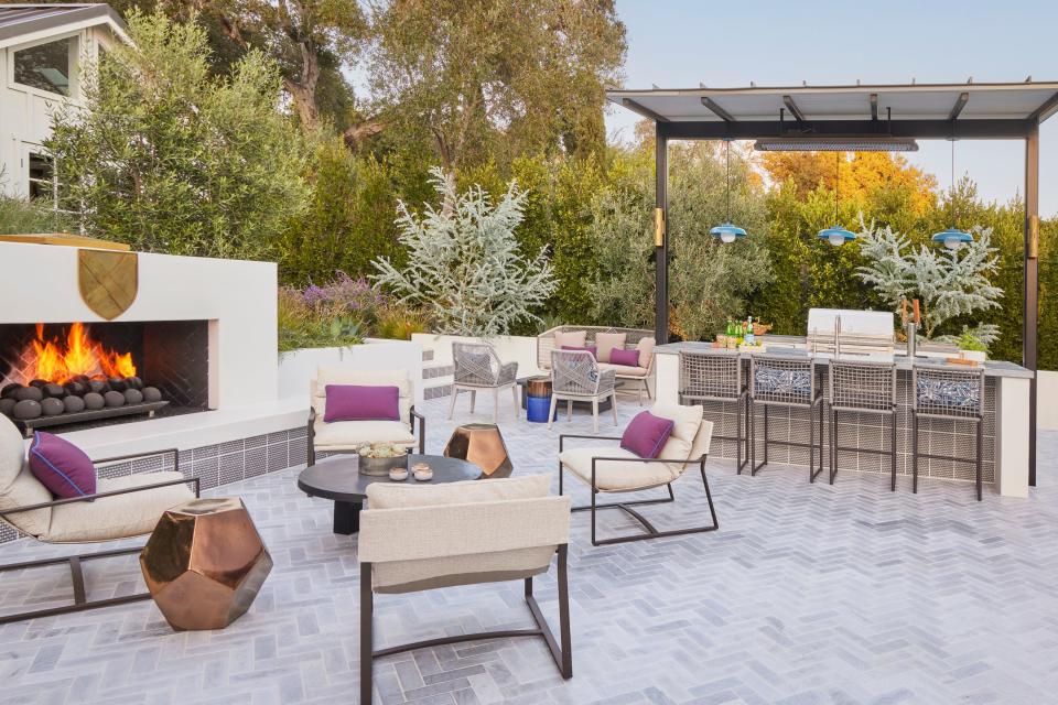 The colorful pillows add a splash of color to the outdoor kitchen area.