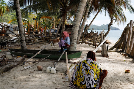 Girls make phone calls while siting on a broken wooden boat at the epicentre of a devastating earthquake at Lende Tovea village in Donggala, Sulawesi island, Indonesia October 6, 2018. REUTERS/Beawiharta