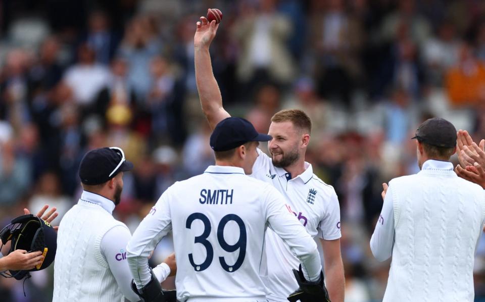 Gus Atkinson raises the ball to the crowd after taking a five-for on his debut