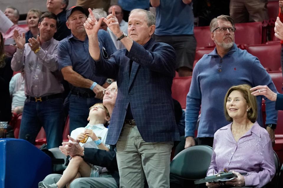 Mar 3, 2022; Dallas, Texas, USA;  Former President George W. Bush gestures the letter "W" to students cheering after he was introduced during the first half at Moody Coliseum.