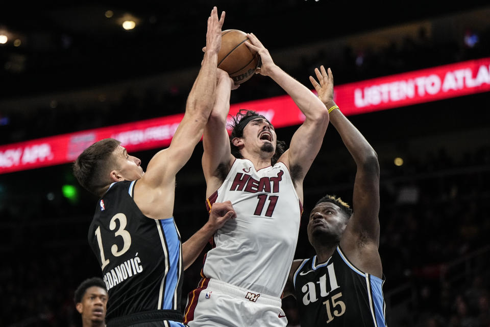 Miami Heat guard Jaime Jaquez Jr. (11) shoots against Atlanta Hawks guard Bogdan Bogdanovic (13) and center Clint Capela (15) during the second half of an NBA basketball game, Saturday, Nov. 11, 2023, in Atlanta. The Miami Heat won 117-109. (AP Photo/Mike Stewart)