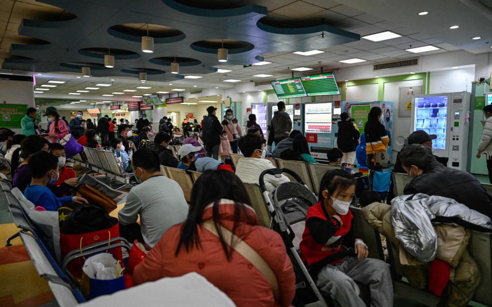 Children and their parents wait at the outpatient clinic of a hospital in Beijing on November 23