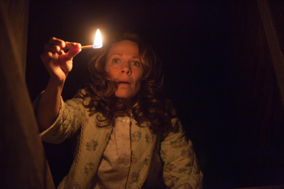 Lili Taylor holds a lit match in a dark stairwell