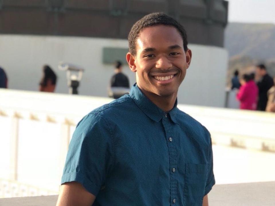 James Curtis standing outdoors in a plaza with a blue shirt