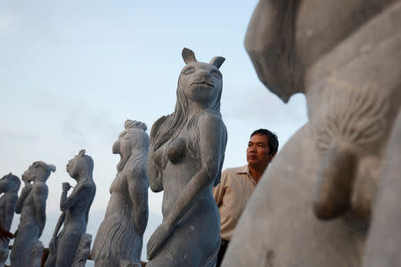 A man watches godlike sculptures with animal heads and human genitalia at Hon Dau resort in Hai Phong city, east of Hanoi, Vietnam April 5, 2018. Picture taken April 5, 2018. REUTERS/Kham