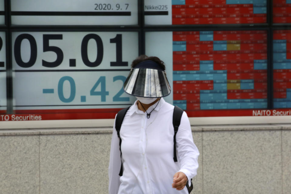 A woman walks by an electronic stock board of a securities firm in Tokyo, Monday, Sept. 7, 2020. Asian stock markets were mixed Monday after Wall Street turned in its biggest weekly decline in more than two months. (AP Photo/Koji Sasahara)