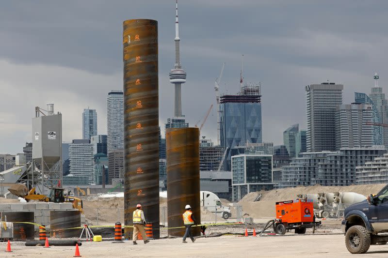 Workers pass construction equipment on an Eastern Waterfront work site in Toronto