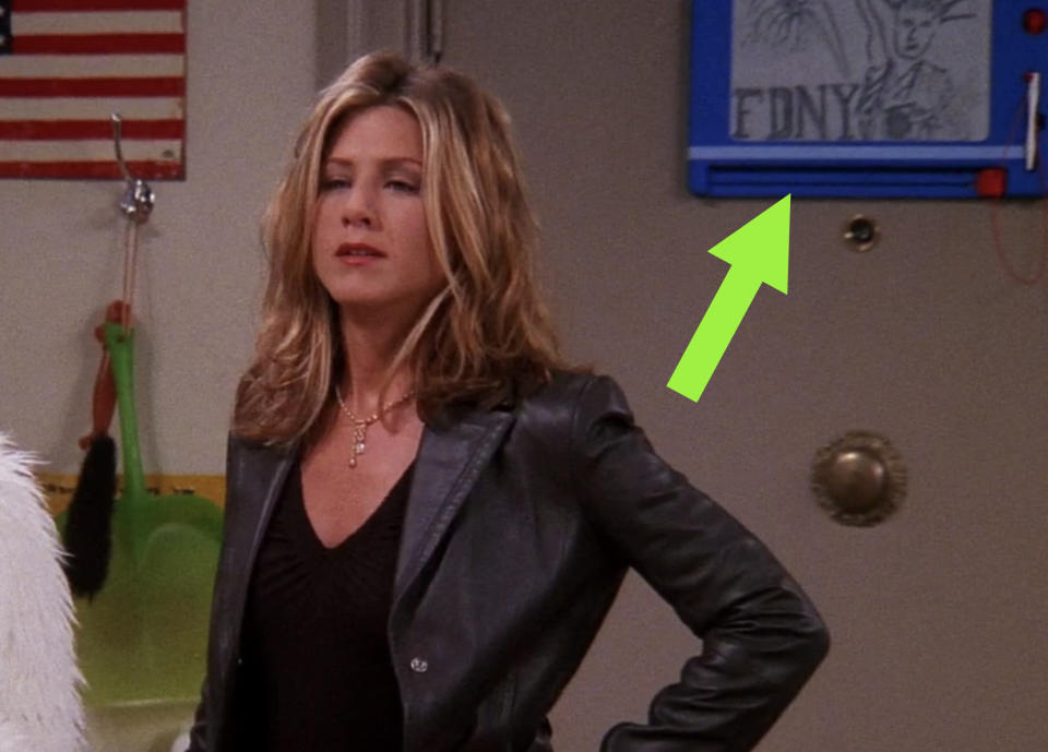 Behind Rachel, there's an Etch a Sketch with a drawing of the Statue of Liberty and the words "FDNY" on it