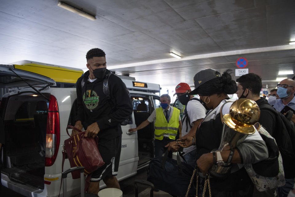 NBA Champion Giannis Antetokounmpo, of the Milwaukee Bucks, who was named NBA Finals Most Valuable Player, talks with his mother, right, who holds his MVP Award, at the Eleftherios Venizelos International Airport, in Athens, Greece, Sunday, Aug. 1, 2021. The NBA champion and finals MVP plans to stay in Greece for a few days, before returning to the U.S., where his girlfriend expects their second child later this month. (AP Photo/Michael Varaklas)