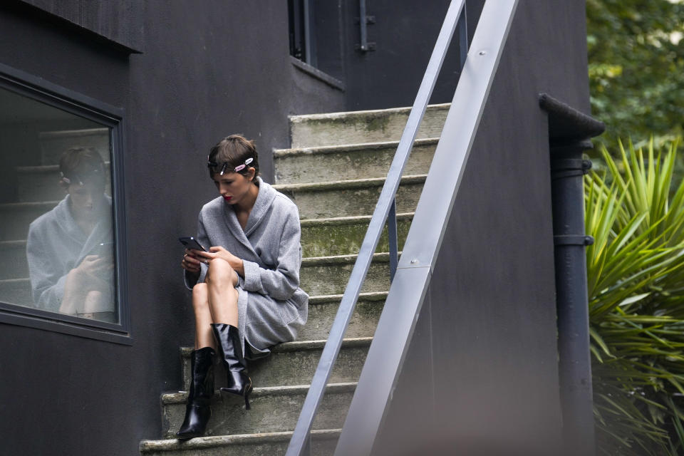 A model checks her phone outside the backstage of the N21 women's Spring Summer 2024 collection presented in Milan, Italy, Wednesday, Sept. 20, 2023. (AP Photo/Luca Bruno)