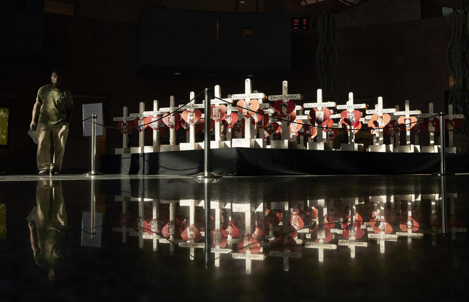 In this Friday, Sept. 21, 2018, photo, a man walks by crosses on display at the Clark County Government Center in Las Vegas. The crosses had been part of a makeshift memorial along the Las Vegas Strip erected in memory of the victims of the Oct. 1, 2017 mass shooting at a country music festival in Las Vegas. A committee chaired by Nevada Gov. Brian Sandoval will work to design, fund and build a permanent memorial. (AP Photo/John Locher)