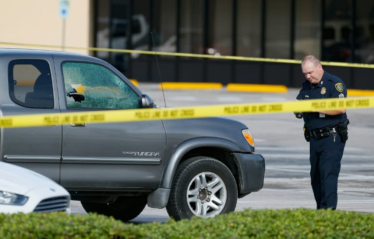 A Houston police investigator photographs a damaged vehicle in the parking lot of a shopping mall where a shooting left nine people wounded on September 26, 2016 in Houston, Texas