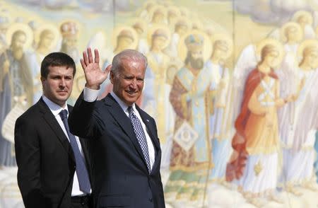 U.S. Vice President Joe Biden (R), followed by a security, waves as he visits Mikhailovskaya Square in Kiev, April 22, 2014. REUTERS/Valentyn Ogirenko