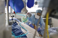 A medical staff member tends to a COVID-19 patient in the intensive care unit of the Strasbourg University Hospital, eastern France, Thursday Jan. 13, 2022. The omicron variant is exposing weaknesses at the heart of Europe's public health system. In France and Britain, a sharp rise in coronavirus hospitalizations coupled with staff falling sick has led to a shortage of beds. (AP Photo/Jean-Francois Badias)