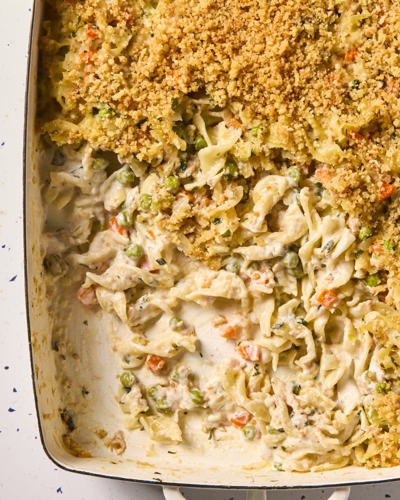 overhead shot of tuna casserole in a white casserole dish, with a scoop taken out of the bottom left corner.
