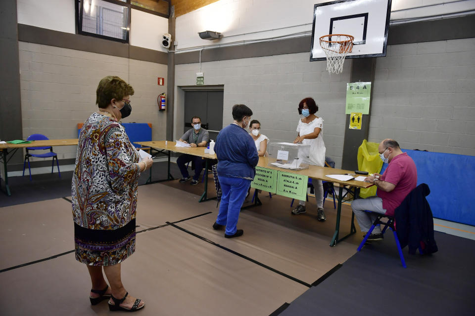 People queue wearing face masks to help curb the spread of the coronavirus in a polling station during the Basque regional election in the village of Durango, northern Spain, Sunday, July 12, 2020. Basque authorities display special rules and practices in the protection against the coronavirus. (AP Photo/Alvaro Barrientos)