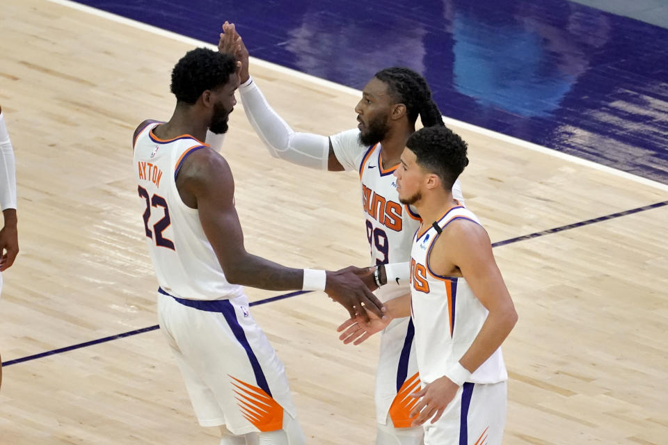 Phoenix Suns forward Jae Crowder (99) celebrates with guard Devin Booker and center Deandre Ayton (22) during the first half of an NBA basketball game against the Houston Rockets, Monday, April 12, 2021, in Phoenix. (AP Photo/Matt York)