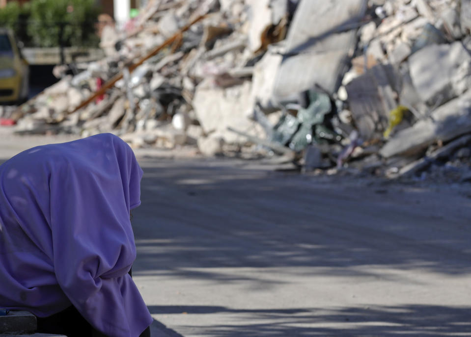 <p>A man sits with a blanket over his head in front of collapsed buildings, in Amatrice, central Italy, Aug. 26, 2016. Strong aftershocks rattled residents and rescue crews alike Friday as hopes began to dim that firefighters would find any more survivors from Wednesday’s earthquake.(Photo: Andrew Medichini/AP) </p>