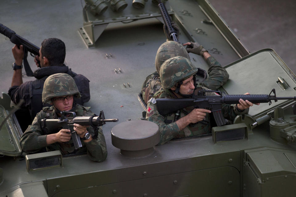 Navy soldiers take position during an operation to occupy the Mare slum complex in Rio de Janeiro, Brazil, Sunday, March 30, 2014. The Mare complex of slums, home to about 130,000 people and located near the international airport, is the latest area targeted for the government's "pacification" program, which sees officers move in, push out drug gangs and set up permanent police posts. (AP Photo/Silvia Izquierdo)