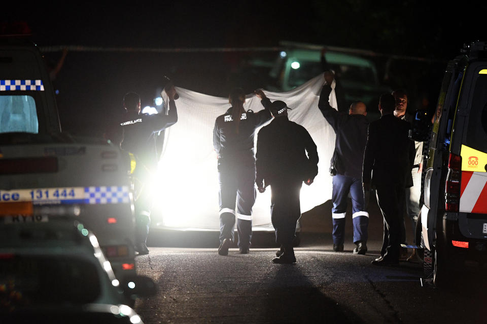 Officers hold up a white sheet at the scene in West Pennant Hills where two teenagers were found shot dead inside a bedroom.Source: AAP