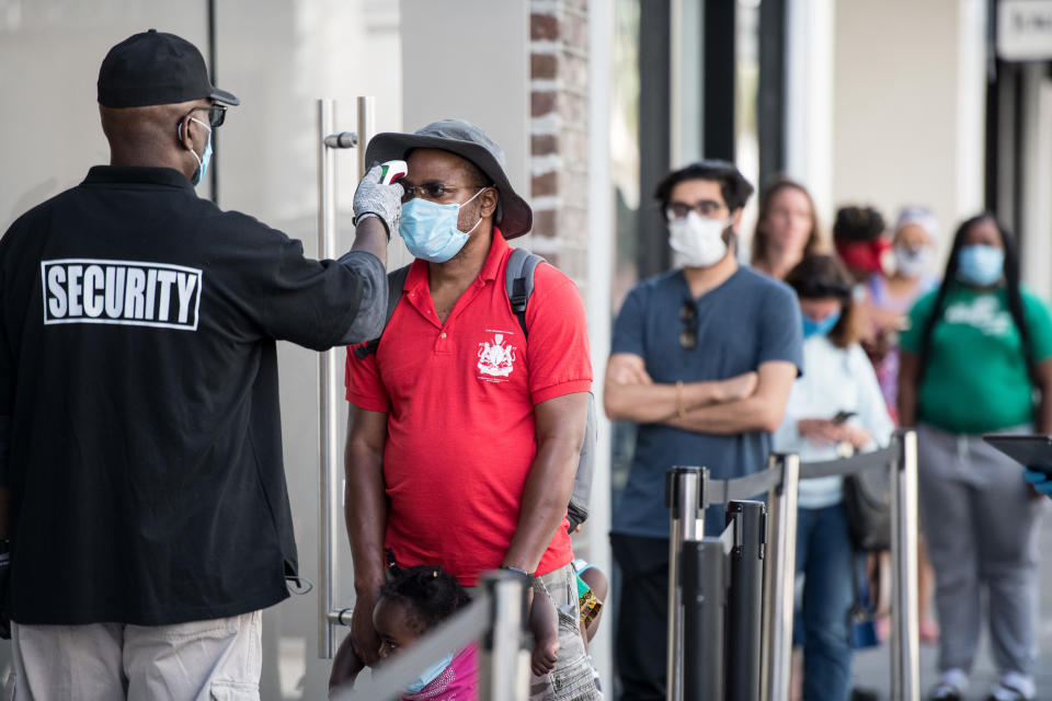 CHARLESTON, SC - MAY 13: A security guard takes the temperature of a customer outside the Apple Store on May 13, 2020 in Charleston, South Carolina. Customers had their temperatures taken and were required to wear masks at the South Carolina store, as locations in Idaho, Alabama, and Alaska reopened as well following forced closures due to the coronavirus. (Photo by Sean Rayford/Getty Images)