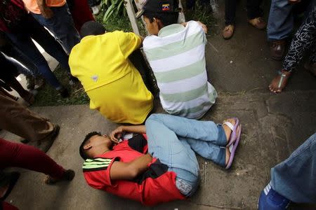 A young man lies on the floor outside a health center as he waits to gets treatment for malaria, in San Felix, Venezuela November 3, 2017. REUTERS/William Urdaneta/Files