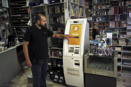 A man demonstrates the use of a Bitcoin ATM at a bookstore in Acharnai in northern Athens, Greece June 30, 2015. REUTERS/Dimitris Michalakis