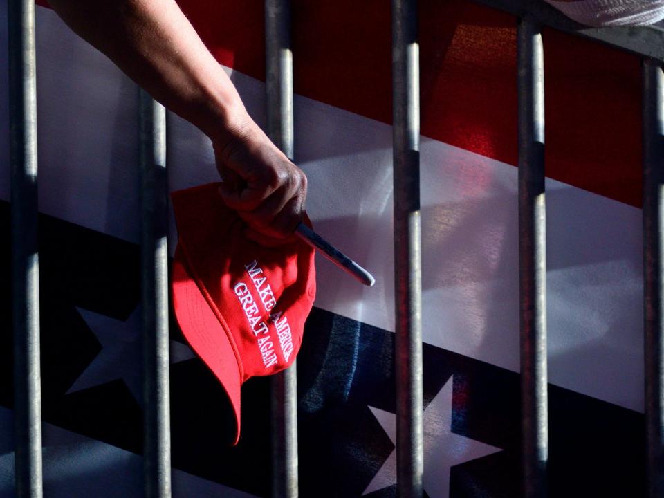 A fan hold out a MAGA caps and sharpies at a 2019 MAGA rally for Donald Trump