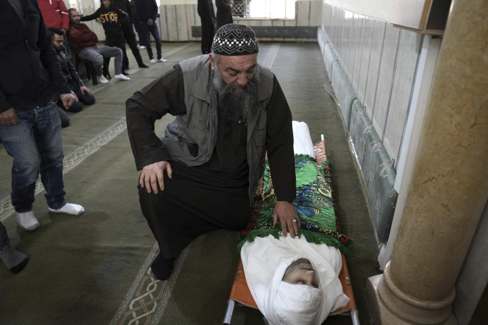 A relative pauses after placing a prayer rug on Nassim Abu Fouda at his funeral in the West Bank city of Hebron, Monday, Jan. 30, 2023. Israeli forces shot and killed the Palestinian man in the flashpoint city in the occupied West Bank on Monday, the Palestinian Health Ministry said. The killing marks the latest bloodshed in spiraling violence that comes as U.S. Secretary of State Antony Blinken visits the region. (AP Photo/ Mahmoud Illean)