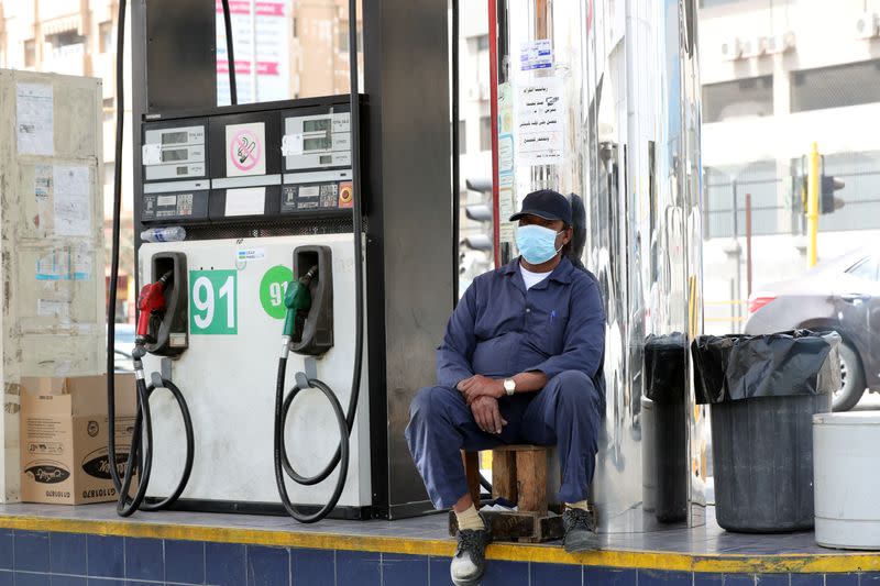 A gas station worker wearing a protective face mask sits next to a petrol station, after Saudi Arabia imposed a temporary lockdown on the province of Qatif following the spread of coronavirus, in Qatif