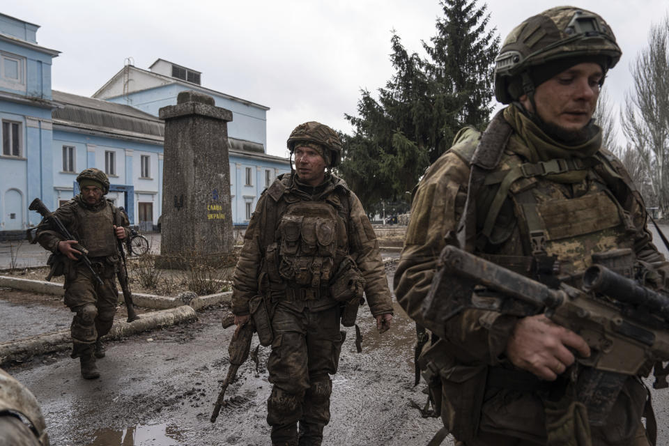 FILE - Ukrainian servicemen who recently returned from the trenches of Bakhmut walk on a street in Chasiv Yar, Ukraine, Wednesday, March 8, 2023. Approval by the U.S. House of a $61 billion package for Ukraine puts the country a step closer to getting an infusion of new firepower. But the clock is ticking. Russia is using all its might to achieve its most significant gains since the invasion by a May 9 deadline. (AP Photo/Evgeniy Maloletka, File)