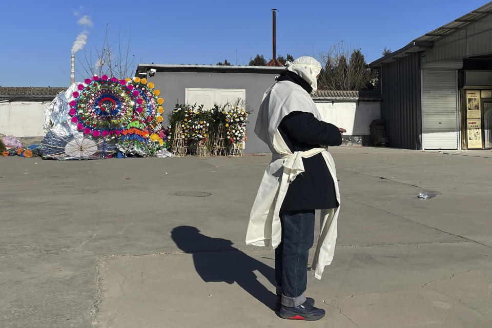 A relative in traditional Chinese funeral attire stands near funeral wreaths at the Gaobeidian Funeral Home in northern China's Hebei province, Thursday, Dec. 22, 2022. Bodies from Beijing, a two-hour drive away are appearing at the Gaobeidian funeral home, because similar funeral homes in Beijing were packed. (AP Photo)