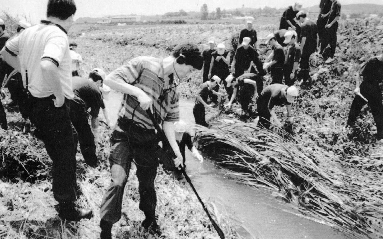 In this July 1993 file photo, investigators examine the scene in Hwaseong, south of Seoul, where a man had raped and brutally killed a woman - Yonhap News Agency