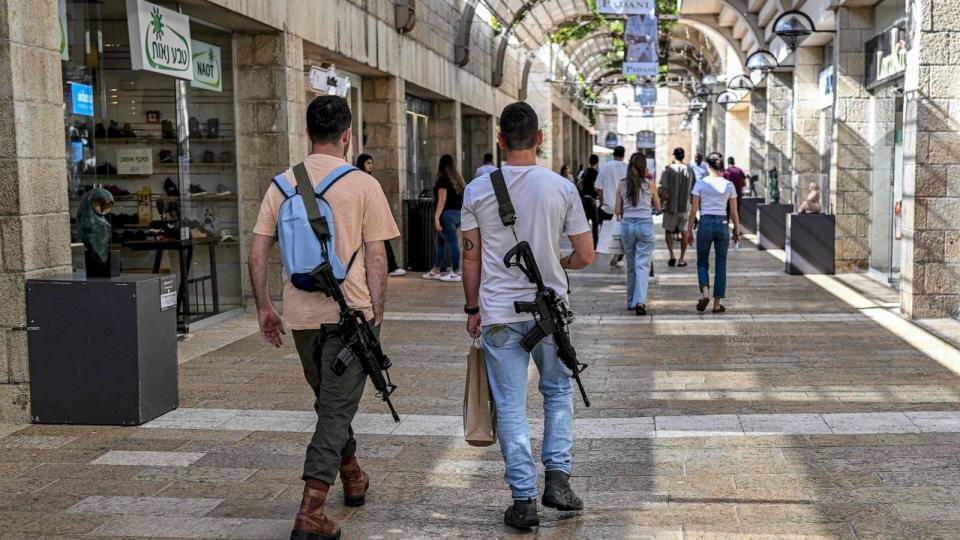 PHOTO: Israeli men, armed with M16 automatic assault rifles, walk in a shopping center in Jerusalem, October 25, 2023. (Yuri Cortez/AFP via Getty Images)
