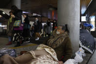 In this Tuesday, Jan. 7, 2020, photo, a homeless woman sits on a sidewalk outside Shinjuku Station with a begging bowl, in Tokyo. Like the U.S., Japan has a relatively high poverty rate for a wealthy nation. It also is less generous with social welfare than countries in Europe, and lacks the sorts of private charities prevalent in the U.S. (AP Photo/Jae C. Hong)