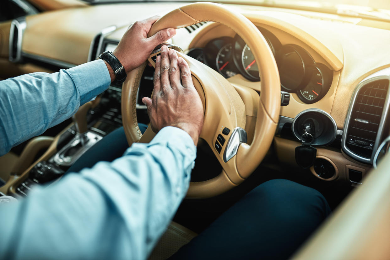 Closeup shot of an unrecognisable businessman pressing the hooter on a steering wheel of a car