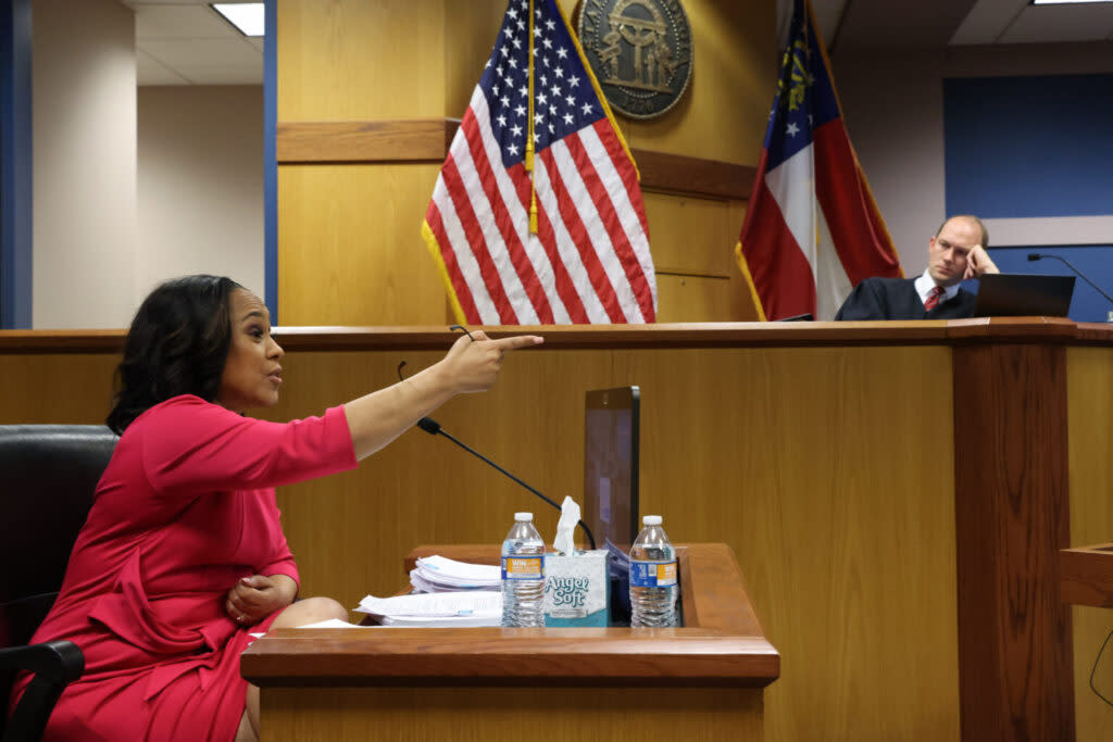 A woman sitting in a witness stand gesturing