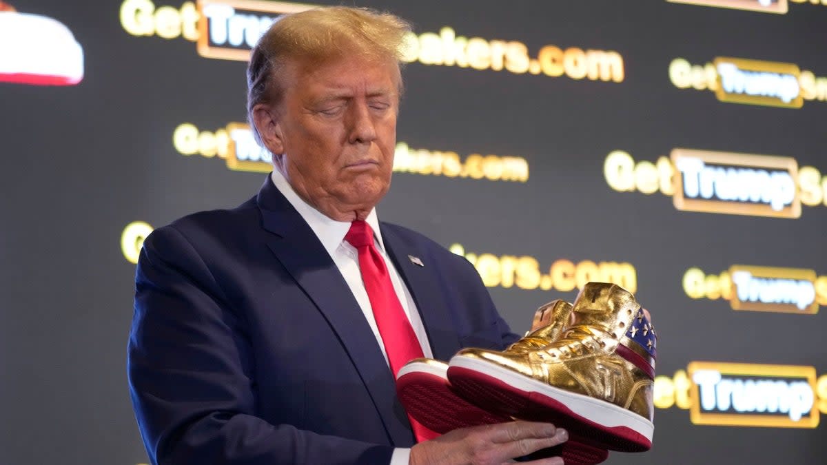 Trump holding his Trump-brand golden trainers (AP)