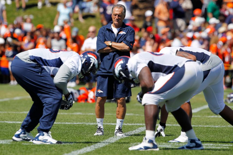 Denver Broncos offensive line consultant Alex Gibbs, back, looks on as linemen take part in drills after the morning session at the team's training camp in Englewood, Colo., Aug. 6, 2013. An innovative offensive line coach, his zone-blocking scheme helped lead the Denver Broncos to back-to-back Super Bowl triumphs in the 1990s. (AP Photo/David Zalubowski, File)