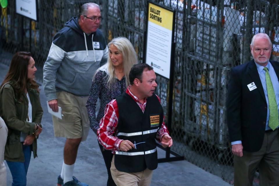 Five people walk through a ballot processing center