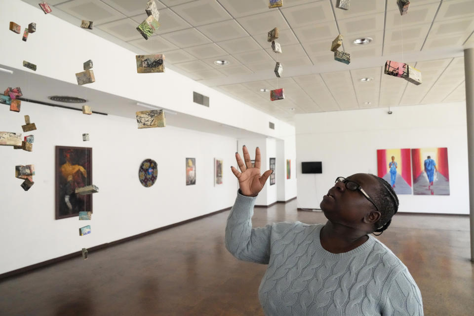 Fadzai Muchemwa, National Art Gallery curator, looks up at some of the art works on display by female artists that have been on show at the southern African country's national gallery since International Women's Day on March 8, in Harare, Friday, April, 14, 2023. The exhibition is titled "We Should All Be Human" and is a homage to women's ambitions and their victories, Muchemwa said. (AP Photo/Tsvangirayi Mukwazhi)