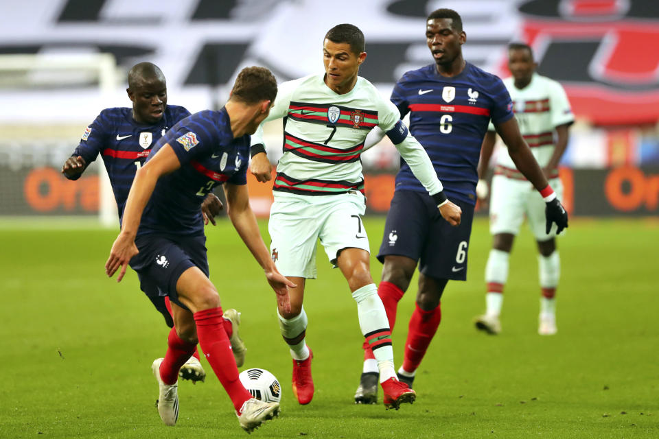 FILE - In this Sunday, Oct. 11, 2020 file photo Portugal's Cristiano Ronaldo, center, runs with the ball at France's Benjamin Pavard, foreground, between Ngolo Kante and Paul Pogba, right, during the UEFA Nations League soccer match between France and Portugal at the Stade de France in Saint-Denis, north of Paris, France. The Portuguese soccer federation says Cristiano Ronaldo has tested positive for the coronavirus. The federation says Ronaldo is doing well and has no symptoms. He has been dropped from the country's Nations League match against Sweden on Wednesday, Oct. 14. (AP Photo/Thibault Camus, File)