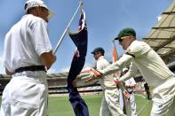 Australia's captain Steve Smith (C) and wicketkeeper Brad Haddin touch the national flag as team enter the ground, on the second day of their 2nd Test match against India, at The Gabba in Brisbane, on December 18, 2014