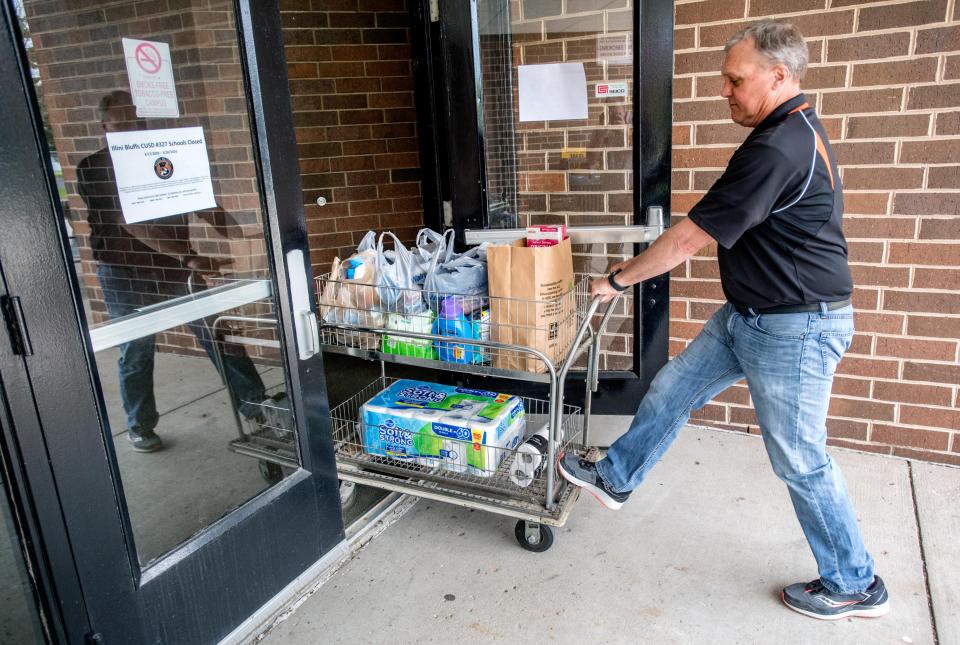 Illini Bluffs School District 327 athletic director Steve Schafer moves a cart of donated items from a dropoff point into the micro food pantry at the high school. The school has hosted the pantry since it closed down due to the COVID-19 pandemic, and it has grown steadily since then. [MATT DAYHOFF/JOURNAL STAR]