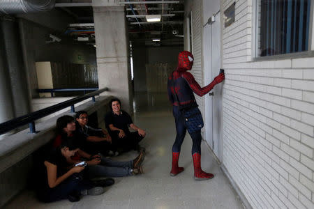 Moises Vazquez, 26, known as Spider-Moy, a computer science teaching assistant at the Faculty of Science of the National Autonomous University of Mexico (UNAM), who teaches dressed as a comic superhero Spider-Man, types his secret code to enter a classroom as his students wait in Mexico City, Mexico, May 27, 2016. REUTERS/Edgard Garrido