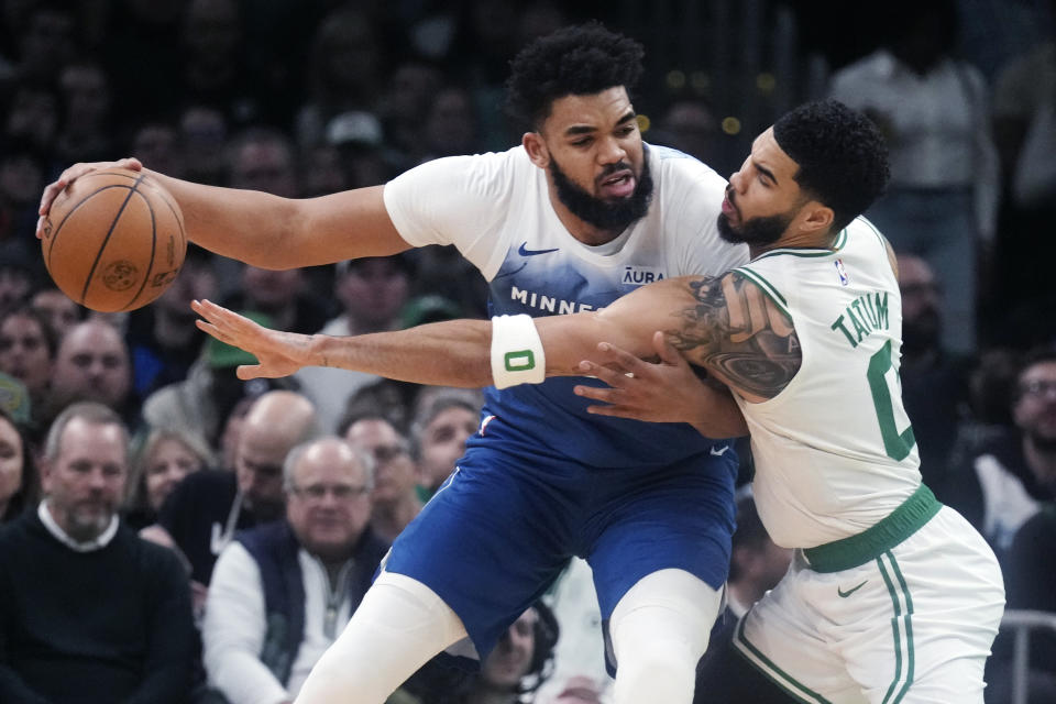 Boston Celtics forward Jayson Tatum (0) tries to steal the ball from Minnesota Timberwolves center Karl-Anthony Towns during the first half of an NBA basketball game Wednesday, Jan. 10, 2024, in Boston. (AP Photo/Charles Krupa)